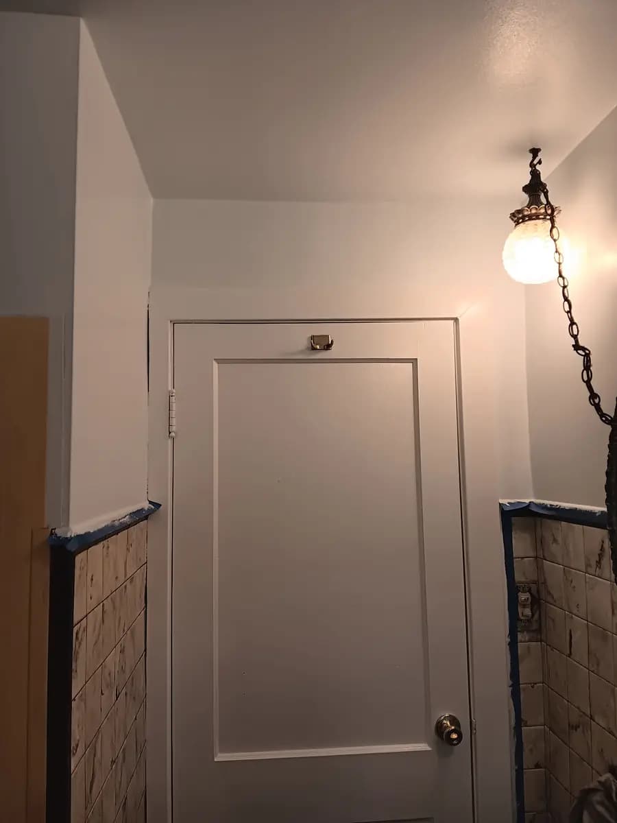 Repainted bathroom door and trim; adjoining tile still masked for protection.