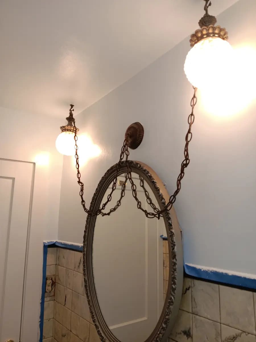 Repainted bathroom wall above the vanity mirror; original tile trim still masked for protection.