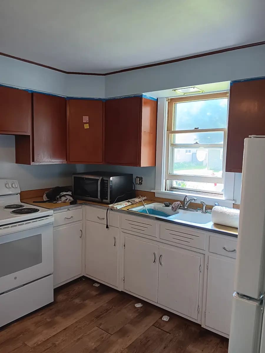 Kitchen ceiling and upper walls repainted; cabinets protected ahead of refinishing.