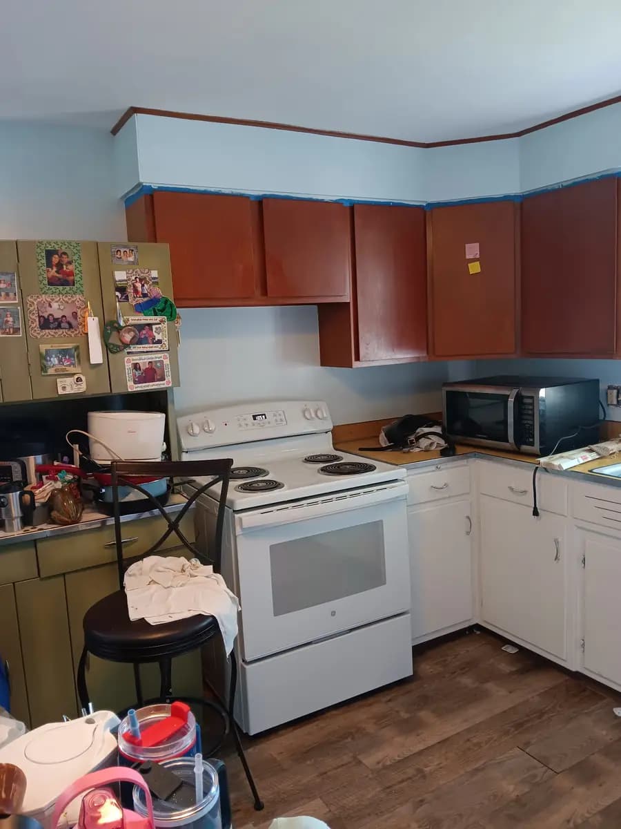 Kitchen walls and trim repainted; cabinet refinishing masked and staged for the next phase.