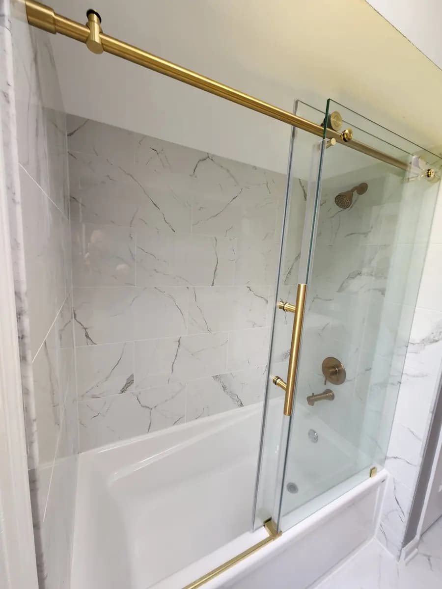 Glass tub door and brass hardware detail in the completed bathroom renovation.