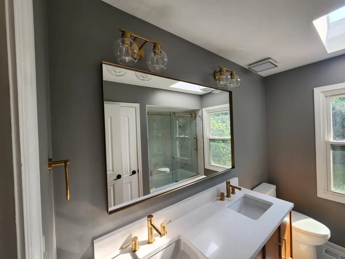 Mirror, vanity, and brass fixture detail in the completed bathroom.
