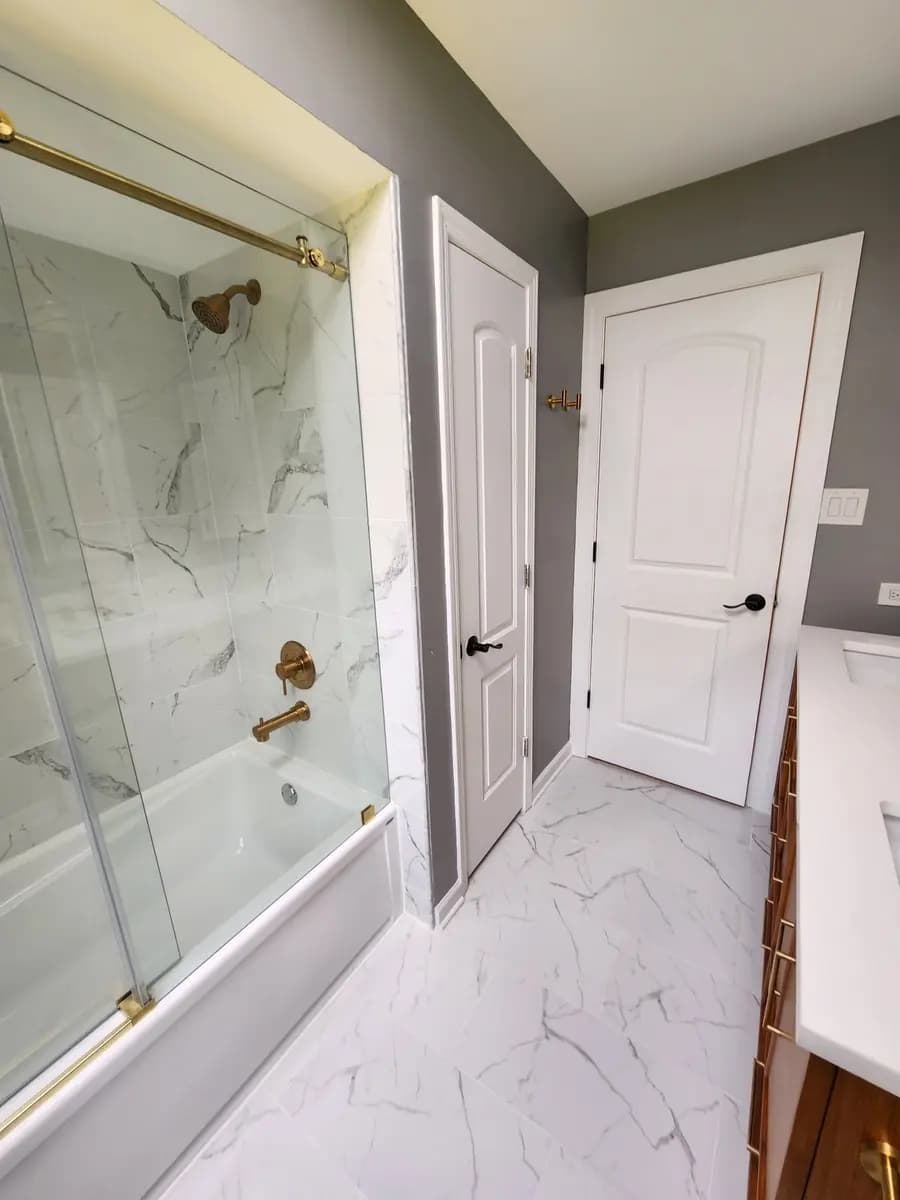 Completed bathroom renovation showing the tub enclosure and finished door trim.