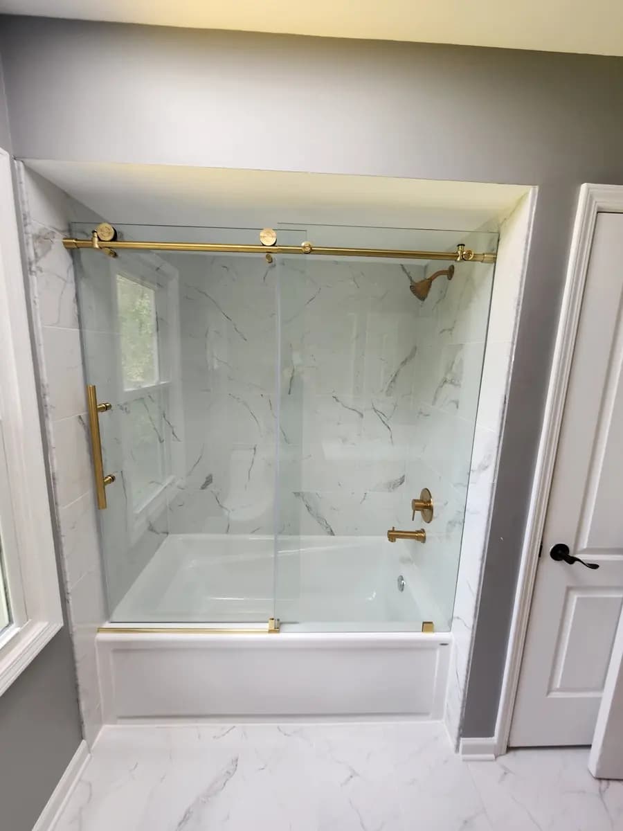 Completed tub surround with marble-look wall finish and brass fixtures.